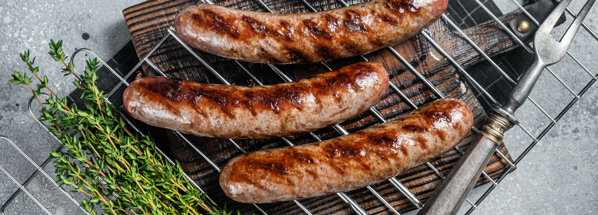 Grilled Sausages On A Wire Rack With Fresh Herbs