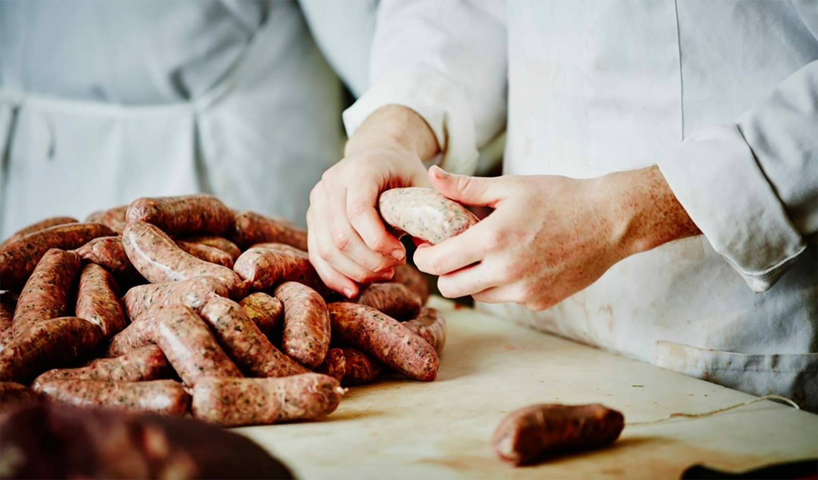 Butchers In White Coats Handcrafting Fresh Sausages