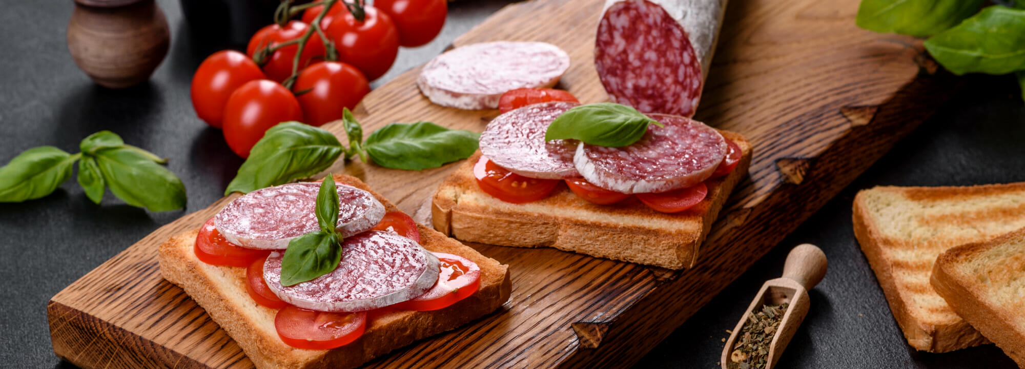 Toasted Bread With Sliced Salami, Cherry Tomatoes, And Fresh Basil