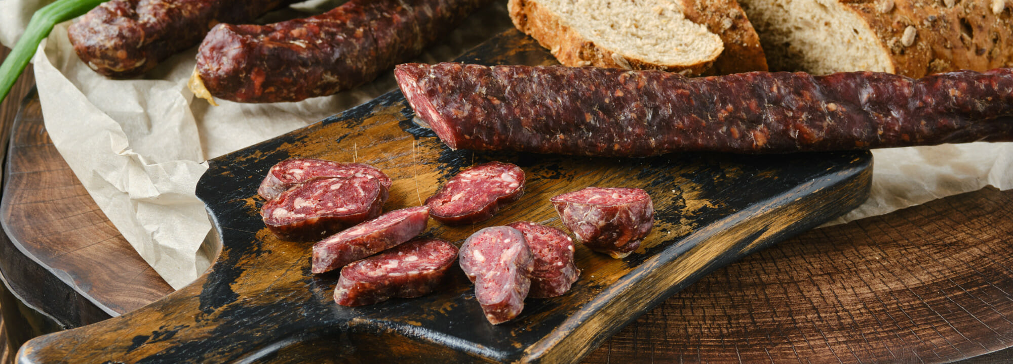 Sliced Dry Sausage On A Rustic Wooden Board With Bread